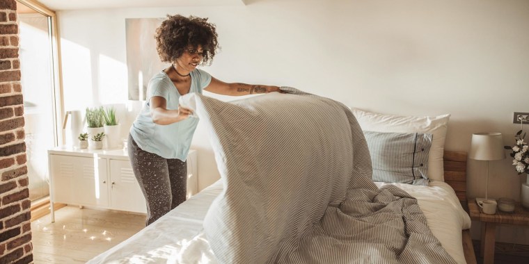 Woman making her bed after changing her sheets