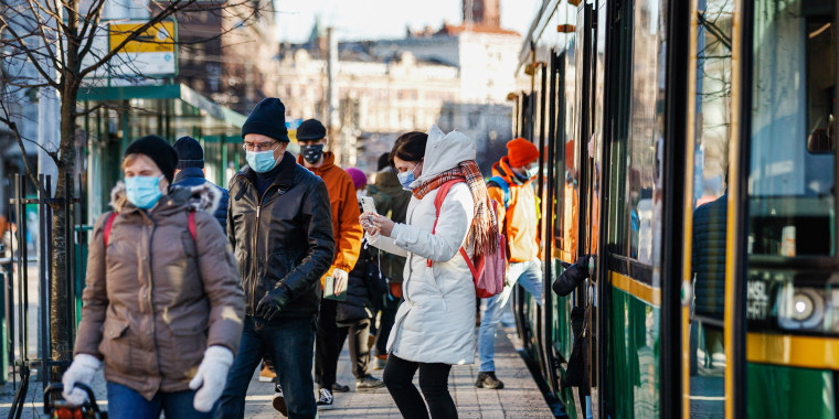 Commuters in Finland hop off a green bus in winter clothing