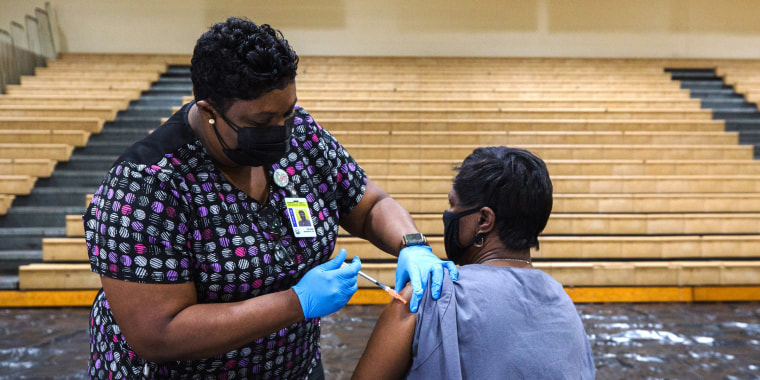 A healthcare worker administers a dose of the Pfizer-BioNTech Covid-19 vaccine to a staff member of the Clarendon School District at Manning High School in Manning, S.C., on March 12, 2021.