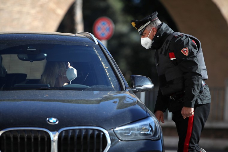 Image: An Italian Carabinieri officer checks the documents of a driver as Rome becomes a "red zone" going into lockdown.