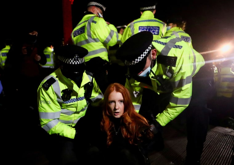 Image: Police detain a woman as people gather at a memorial site in Clapham Common Bandstand, following the kidnap and murder of Sarah Everard, in London, Britain