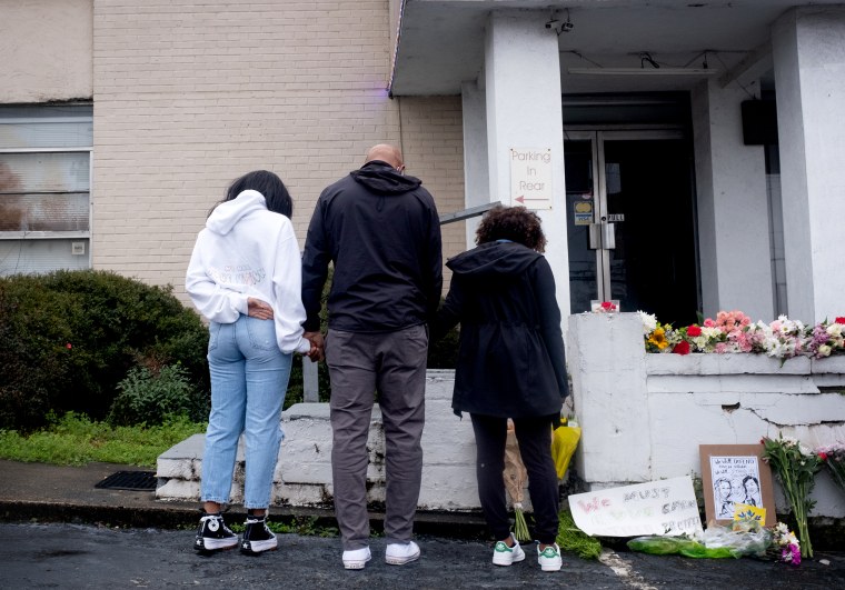 Image: Members of the Lavette family join hands and leave flowers at a memorial outside of Gold Spa in Atlanta on Wednesday.