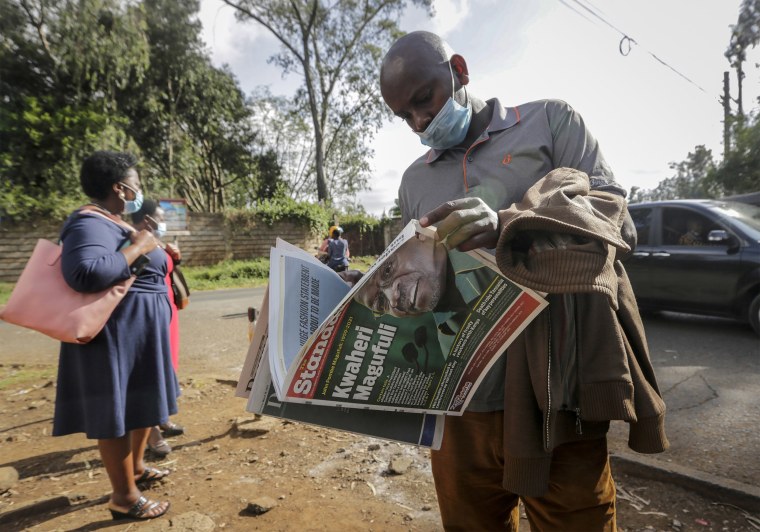 Image: A man reads a copy of the Daily Nation morning newspaper reporting the death of neighboring Tanzania's President John Magufuli on a street in Nairobi, Kenya Thursday