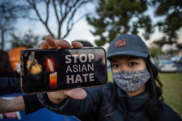 Image: Julie Tran holds her phone during a candlelight vigil in Garden Grove, Calif.,
