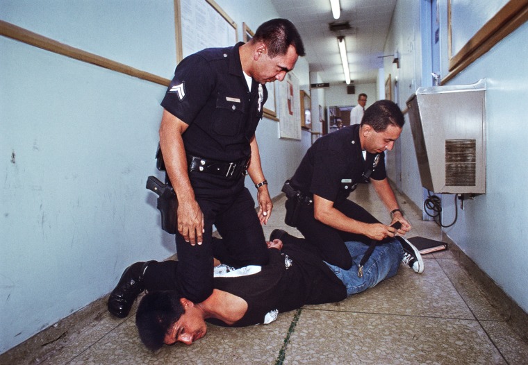 Officers at the Rampart Station restrain a man resisting arrest.