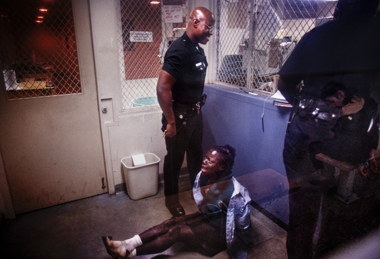 A handcuffed woman is detained and booked at Rampart Station