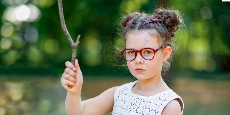 Little girl in red glasses, holding a stick, pretending it is a wand, with a Harry Potter scar on her forehead