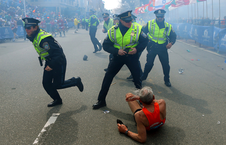 Image: Bill Iffrig, 78, lies on the ground as police officers react to a second explosion at the finish line of the Boston Marathon