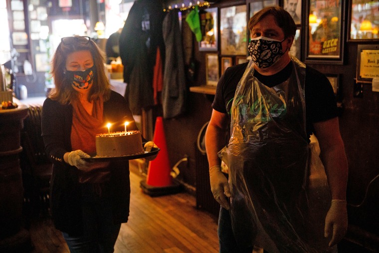 Helen Buford, owner of Julius', carries a birthday cake alongside Gerry Gonzalez to Bronwyn Rucker and Jimmy Tomkins, longtime customers who were celebrating their birthdays on March 19.