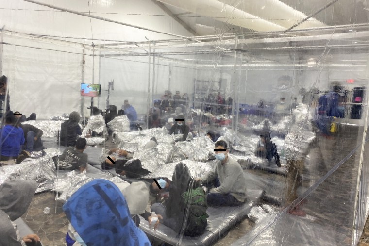 Migrants crowd a room with walls of plastic sheeting at the U.S. Customs and Border Protection temporary processing center in Donna, Texas, in a partially obscured photograph released March 22, 2021.