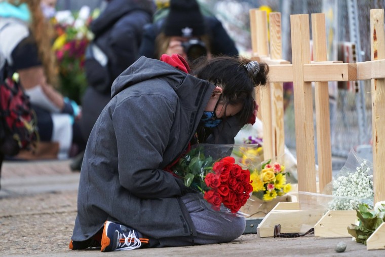 Star Samkus, who works at the King Soopers grocery store and knew three of the victims of the mass shooting there, cries while kneeling in front of crosses placed in honor of the victims on March 23, 2021, in Boulder, Colo.