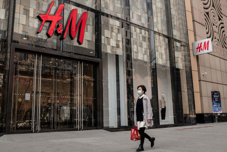 Image: A woman walks past a store of Swedish clothing giant H&amp;M in Beijing