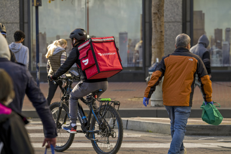 IMAGE: A bike messenger carries a DoorDash bag in San Francisco.