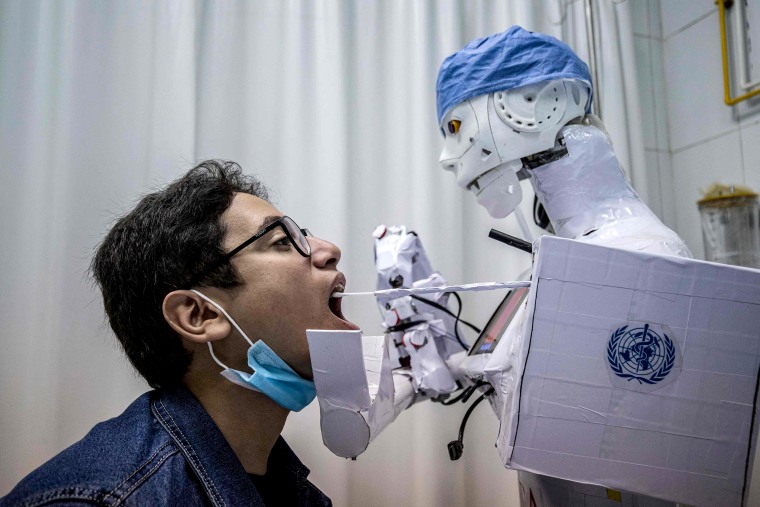 Image: A prong extending from a remote-controlled robot prototype approaches the mouth of a volunteer to extract a throat swab sample