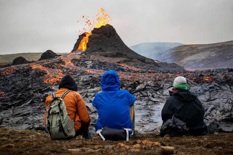 Image: Sunday hikers look at the lava flowing from the erupting Fagradalsfjall volcano some 40 km west of the Icelandic capital Reykjavik, on March 21, 2021.
