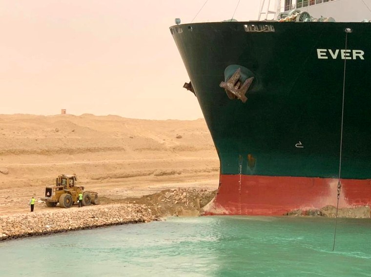Image: Workers are seen next to a container ship which was hit by strong wind and ran aground in Suez Canal, Egypt on March 24, 2021.