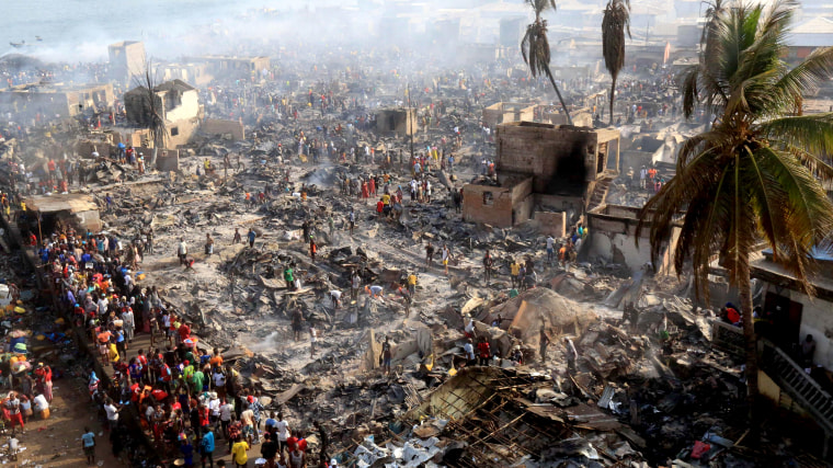 Image: People look on at the aftermath of a large fire that broke out in an informal settlement in Susans Bay, Freetown on March 25, 2021.