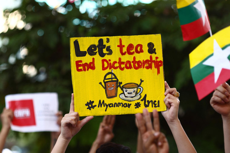 Image: Myanmar migrants in Thailand holds signs relating to the \"Milk Tea Alliance\" as they take part in a protest in Bangko