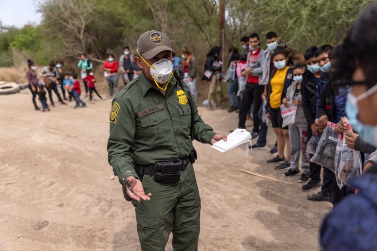 A U.S. Border Patrol agent questions an unaccompanied minor after a group of asylum seekers crossed the Rio Grande into Texas on March 25, 2021 in Hidalgo, Texas.