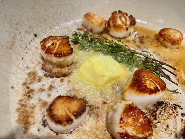 With a minute to go, if you want additional flavor, add butter to the pan and allow it to melt, throwing in sprigs of thyme as well and basting the scallops.