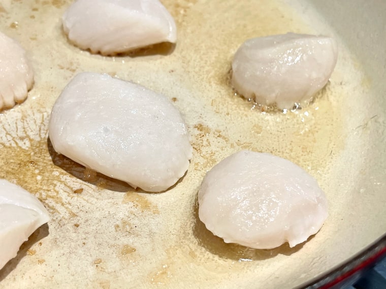 When the pan is scorching hot, add the scallops to the pan. You want to make sure to leave a bit of space between each scallop.