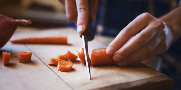 Close-up of woman chopping carrot on cutting board