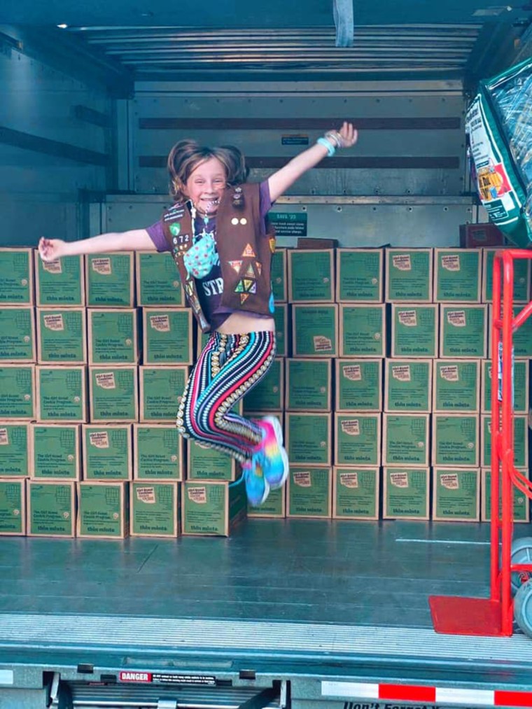 Lilly poses with the boxes of cookies her customers have donated to people in need this season.
