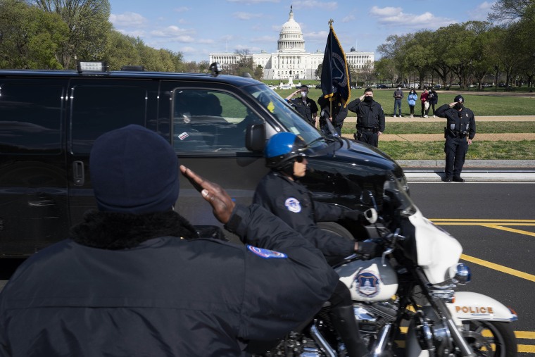 With the U.S. Capitol in the background, U.S. Capitol Police officers salute as procession carries the remains of a U.S. Capitol Police officer who was killed after a man rammed a car into two officers at a barricade outside the Capitol in Washington, Friday, April 2, 2021.