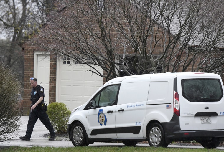 Image: A police officer walks away from a home where at least two people were found dead in Baldwin, Md