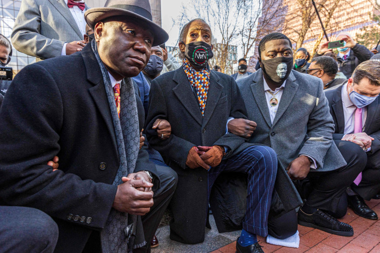 Floyd family lawyer, Attorney Ben Crump (L) and Rev. Al Sharpton, the founder and President of National Action Network,(C) and George Floyd's brother kneel outside the Hennepin County Government Center on Monday March 29, 2021.