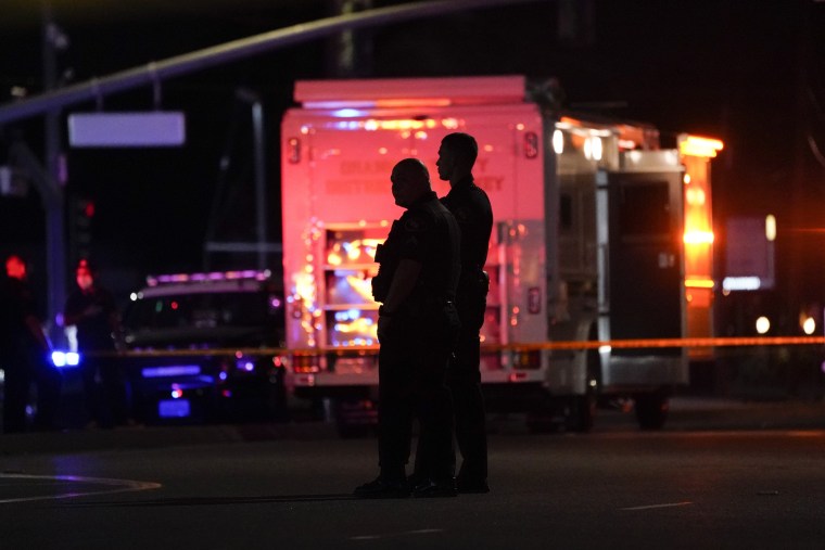 Two police officers stand outside an office building where a shooting occurred in Orange, Calif., Wednesday, March 31, 2021.