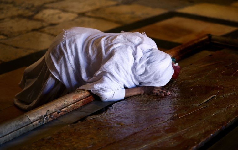 A Christian believer prays on the Stone of Anointing, the place believed to be where Jesus Christ's body was laid after being taken down from the cross, during a mass on Easter Sunday at the Church of the Holy Sepulchre in Jerusalem.