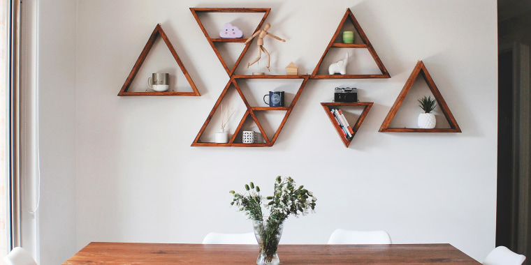 Image of dining room with a wooden table and wooden triangle wall shelves, decorating a blank white wall