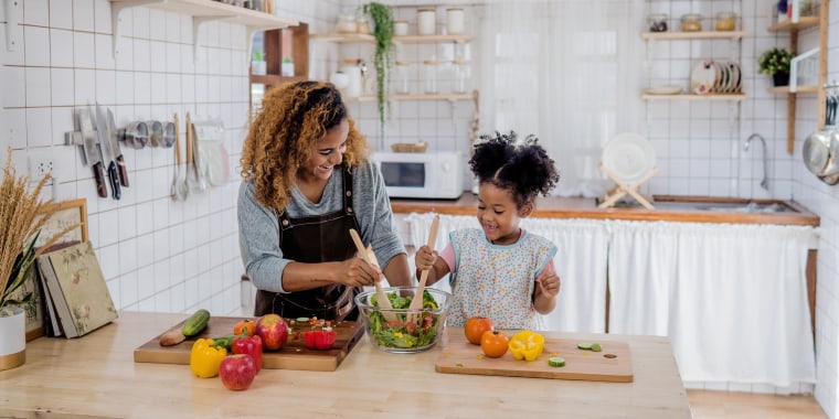 Mom and daughter in kitchen, chopping vegetables on their wooden kitchen island