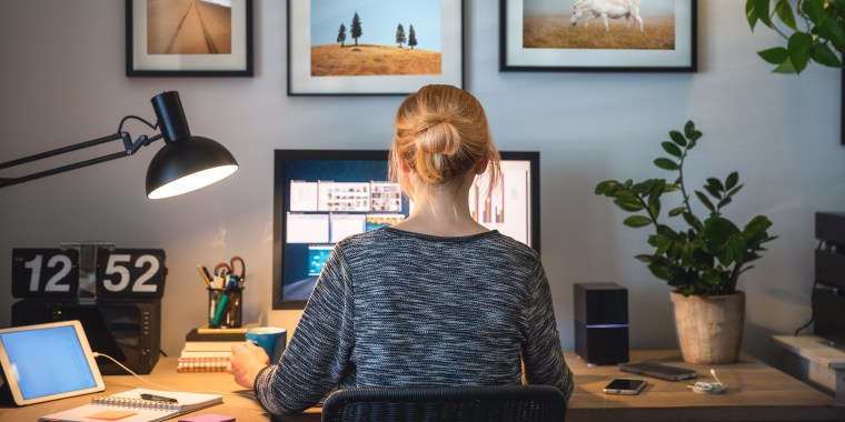 Woman sitting at her work from home desk, surrounded by desk accessories