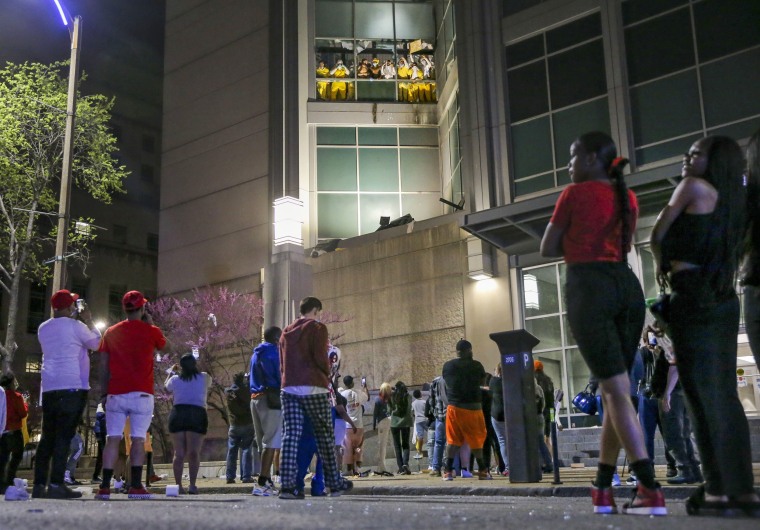 Image: Onlookers watch from the street as inmates chant and throw things from broken windows at the St. Louis Justice Center on April 4, 2021.