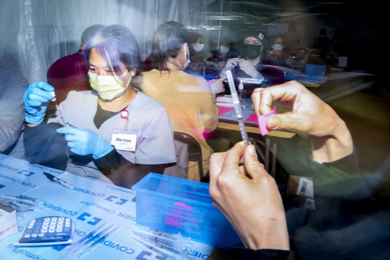 UCHealth pharmacist Marissa Kim, left, prepares a dose of the Pfizer Covid-19 vaccine during a mass vaccination event on Feb. 20, 2021 in Denver, Colo.