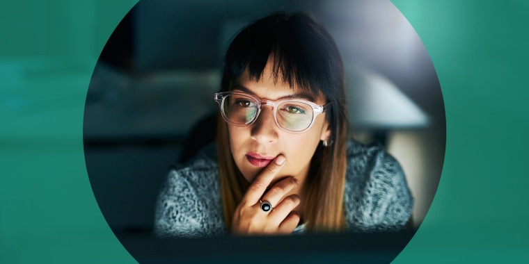 Woman looking at her computer at night, wearing blue light glasses. When shopping for the best blue light glasses, look for yellow lenses. Learn more about the benefits and shop the best blue light glasses.