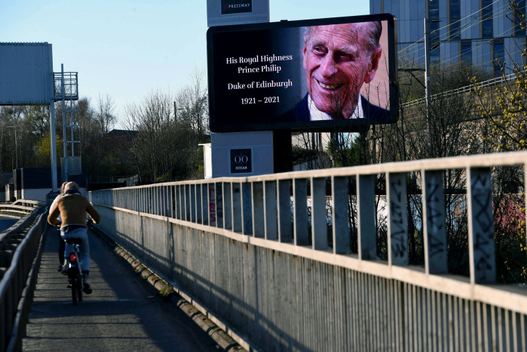 Image: Cyclists pedal past a billboard with an image of Britain's Prince Philip, Duke of Edinburgh alongside the Clydeside Expressway in Glasgow, Scotland on April 9, 2021.