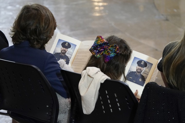 Logan and Abigail Evans look through the programs at the memorial service for their dad, slain Capitol Police officer William Evans.