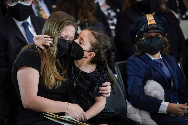 Abigail Evans rests her face against her mother's at her father's memorial service.