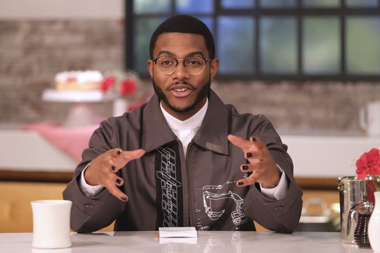 Onwuachi seated behind a counter in smart glasses appears to explain something with hand gestures