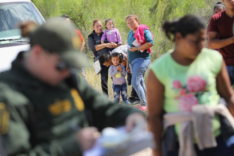 Image: Central American asylum seekers wait as U.S. Border Patrol agents take them into custody