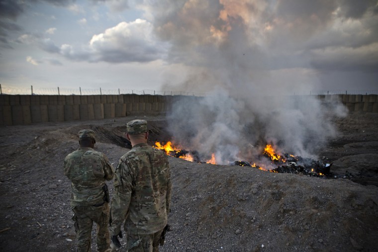 U.S. Army soldiers watch garbage burn in a burn-pit at Forward Operating Base Azzizulah in Kandahar Province, Afghanistan, in 2013.