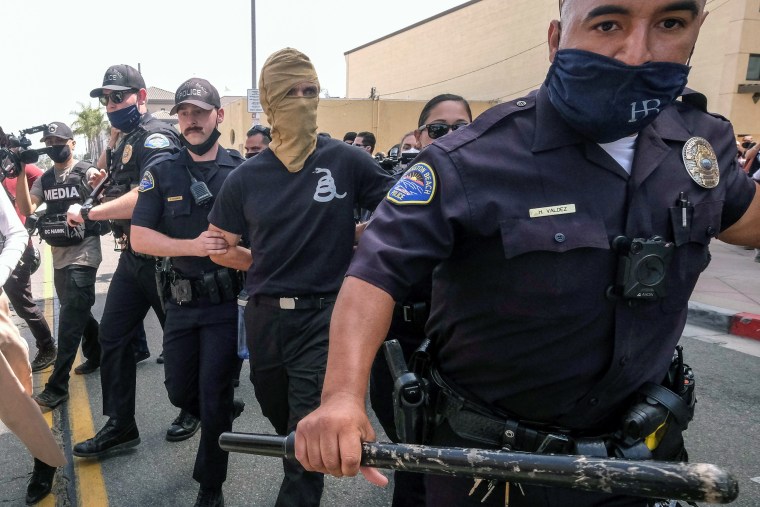 Image: Police detain a demonstrator during a \"White Lives Matter\" protest in Huntington Beach, Calif., on April 11, 2021.