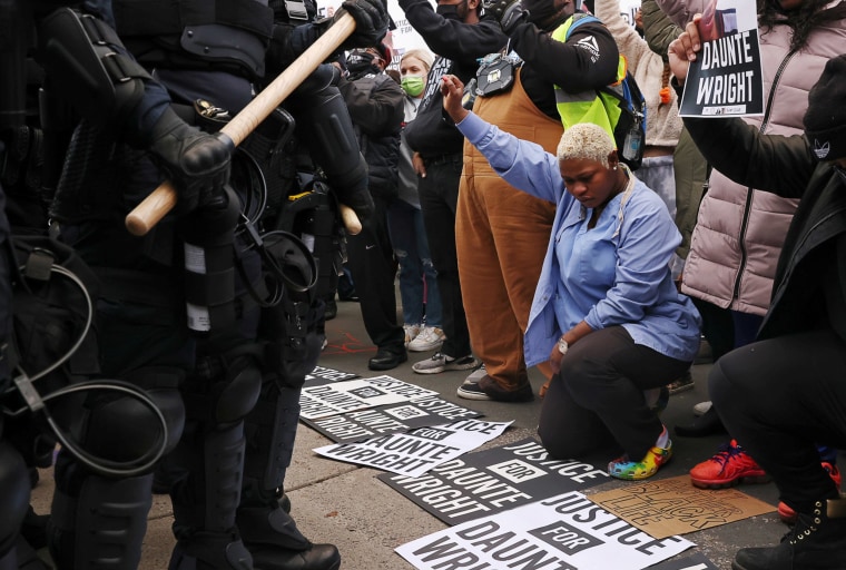 Image: Evelyn Jarbah kneels as protesters take a moment of silence during a rally outside Brooklyn Center Police Department, a day after Daunte Wright was shot and killed by a police officer, in Brooklyn Center, Minn.