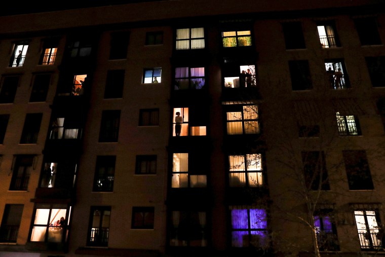 Image: People look out of their apartment windows to show gratitude to healthcare workers during the coronavirus outbreak in Madrid on March 14, 2020.