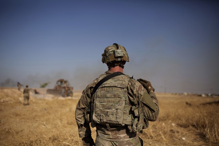 A U.S. special forces soldier watches Syrian Kurdish soldiers dismantle a fortification in the so-called "safe zone" on the border with Turkey near Tal Abyad, Syria on Sept. 6, 2019.