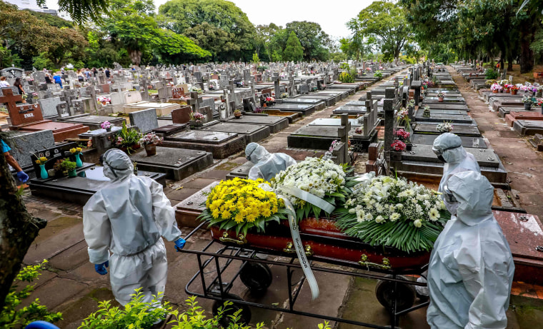 Image: Cemetery workers carry a coffin during the burial of a victim of Covid-19 at the Sao Joao municipal cemetery in Porto Alegre, Brazil, on March 26, 2021.