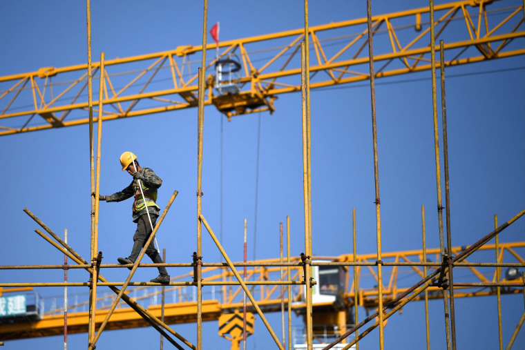 Image: A worker walks along scaffolding at a construction site in Beijing